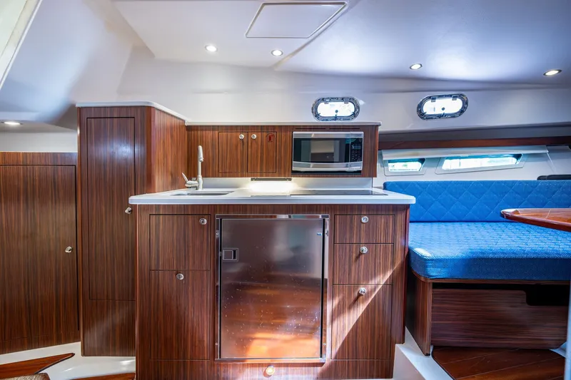 Slide: The Image of Luxurious Pursuit yacht interior with wood cabinetry, kitchenette, and blue seating. - 43
