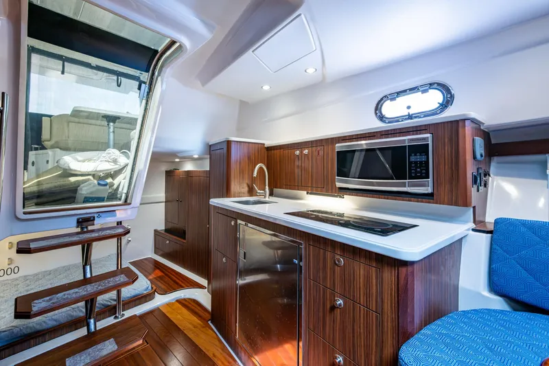Slide: The Image of Luxurious Pursuit yacht interior with modern kitchen, wooden cabinetry, and sleek appliances. - 46