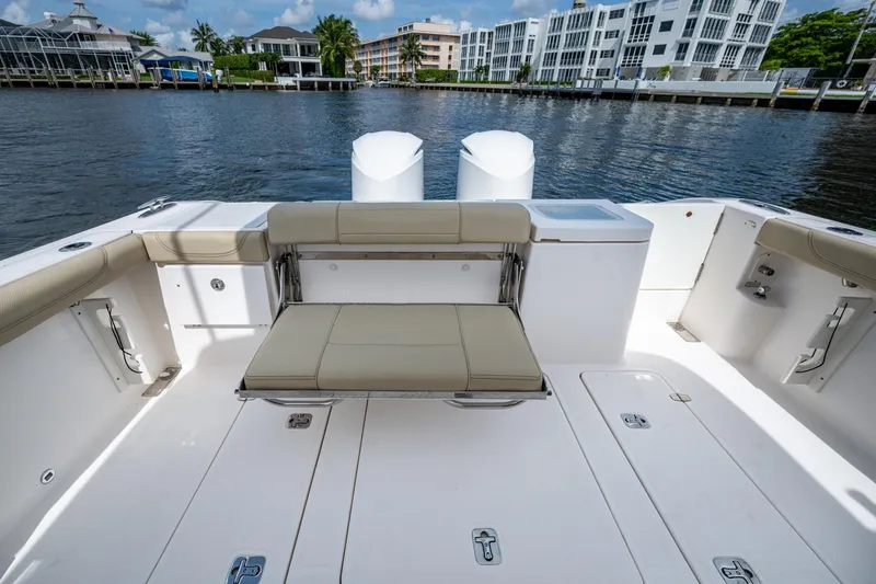 Slide: The Image of Spacious Pursuit boat deck with seating, overlooking waterfront buildings and calm water. - 48