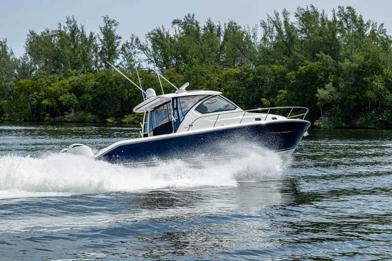 Slide: The Image of Pursuit boat cruising on a scenic waterway with lush green trees in the background. - 5