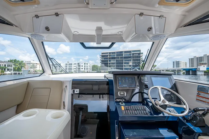 Slide: The Image of Interior view of a Pursuit boat cockpit with modern controls and waterfront cityscape. - 50