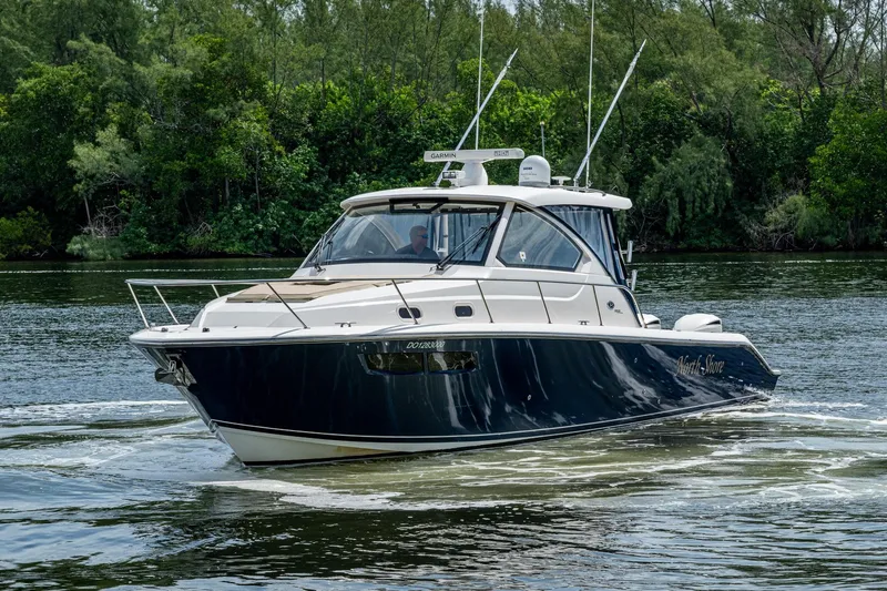 Slide: The Image of Pursuit boat cruising on a calm river with lush green trees in the background. - 51