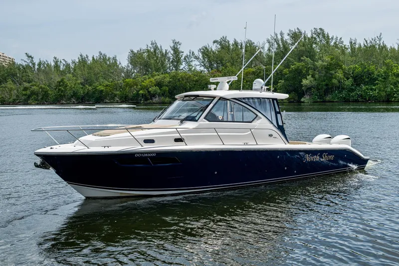 Slide: The Image of Pursuit boat "North Shore" cruising on a calm river with lush greenery. - 52