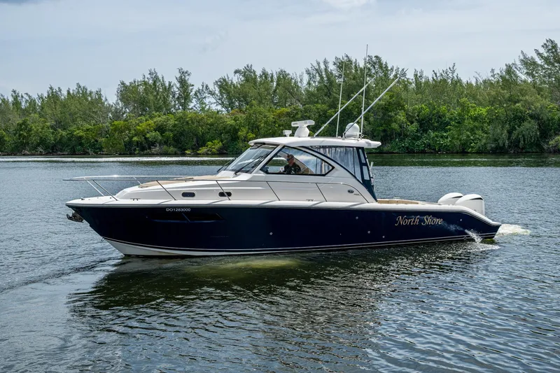 Slide: The Image of Pursuit boat "North Shore" cruising on a calm river with lush greenery. - 54