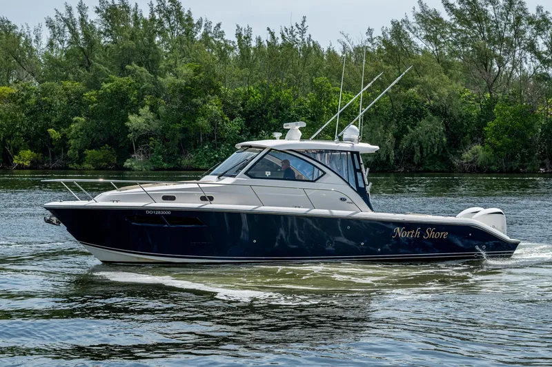 Slide: The Image of Pursuit boat "North Shore" cruising on a calm river with lush greenery backdrop. - 55