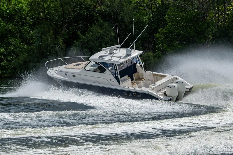 Slide: The Image of Pursuit boat speeding on water, creating waves, surrounded by lush greenery. - 56