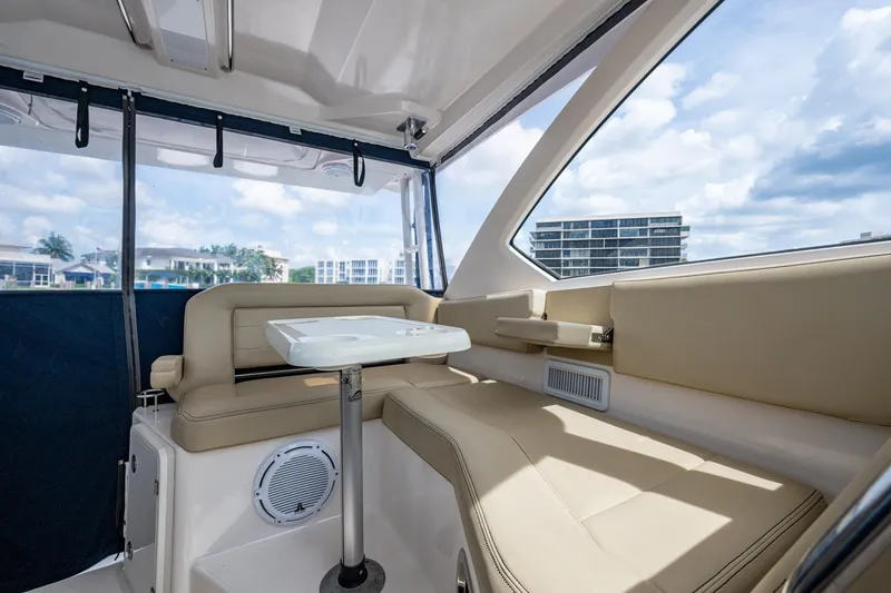 Slide: The Image of Interior of a Pursuit boat with beige seating and a white table, overlooking waterfront buildings. - 57