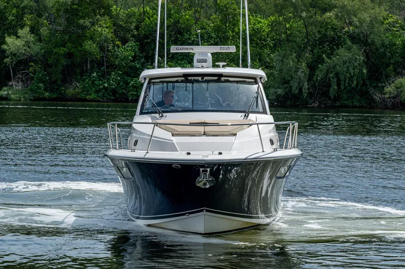 Slide: The Image of Front view of a Pursuit boat cruising on a calm river with lush greenery. - 60