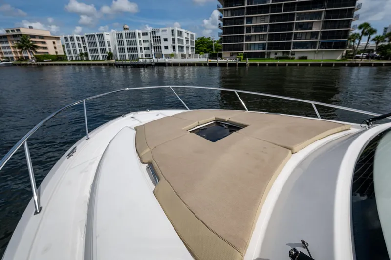 Slide: The Image of Bow of Pursuit boat with sunpad, overlooking waterfront buildings and calm water. - 61