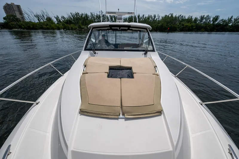 Slide: The Image of Pursuit boat with cushioned deck, cruising on calm water near lush shoreline. - 62
