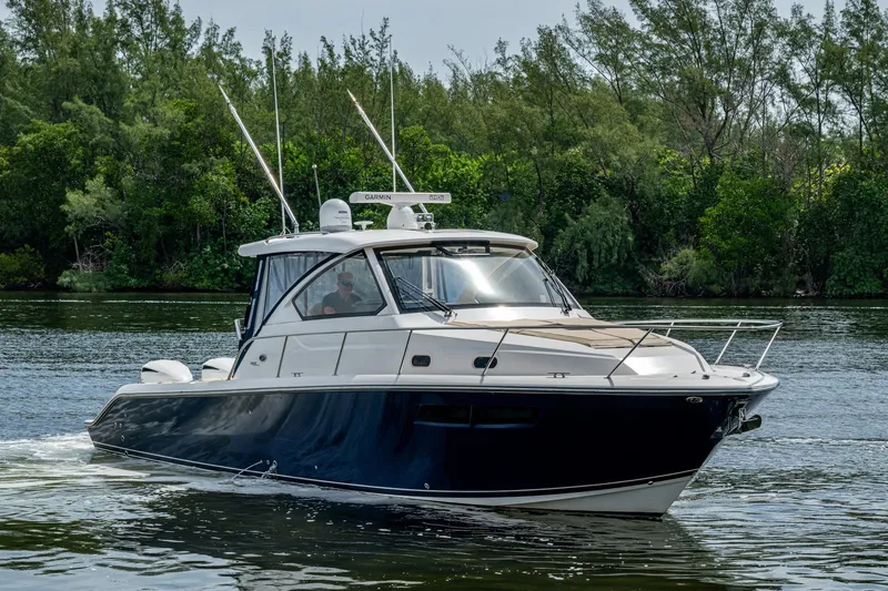Slide: The Image of Pursuit boat cruising on a calm river with lush green trees in the background. - 63