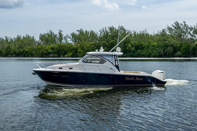 Slide: The Image of Pursuit boat "North Shore" cruising on a calm river with lush green trees. - 65