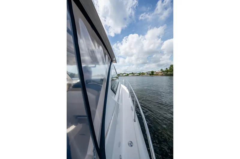 Slide: The Image of Side view of a Pursuit boat cruising on a calm waterway under a partly cloudy sky. - 67