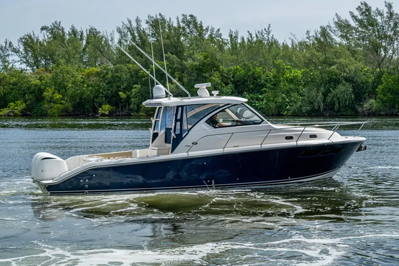 Slide: The Image of A Pursuit boat cruising on a calm river with lush green trees in the background. - 68