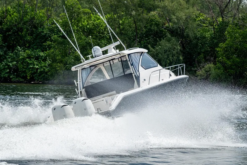 Slide: The Image of A Pursuit boat speeding on water, creating a large wake, surrounded by lush greenery. - 72
