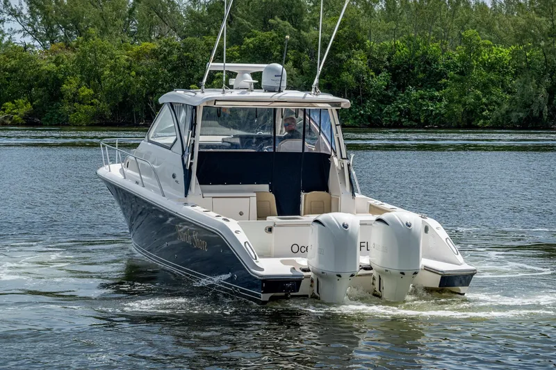 Slide: The Image of Pursuit boat cruising on a river with dual outboard engines, surrounded by lush greenery. - 74