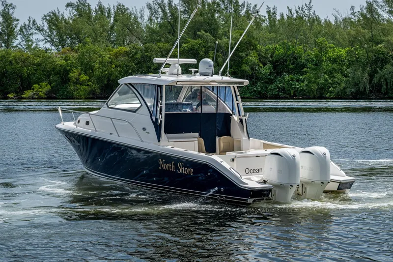 Slide: The Image of Pursuit boat cruising on a calm river with lush green trees in the background. - 77