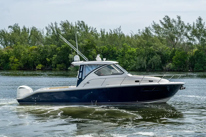 Slide: The Image of Pursuit boat cruising on a calm river with lush green trees in the background. - 78