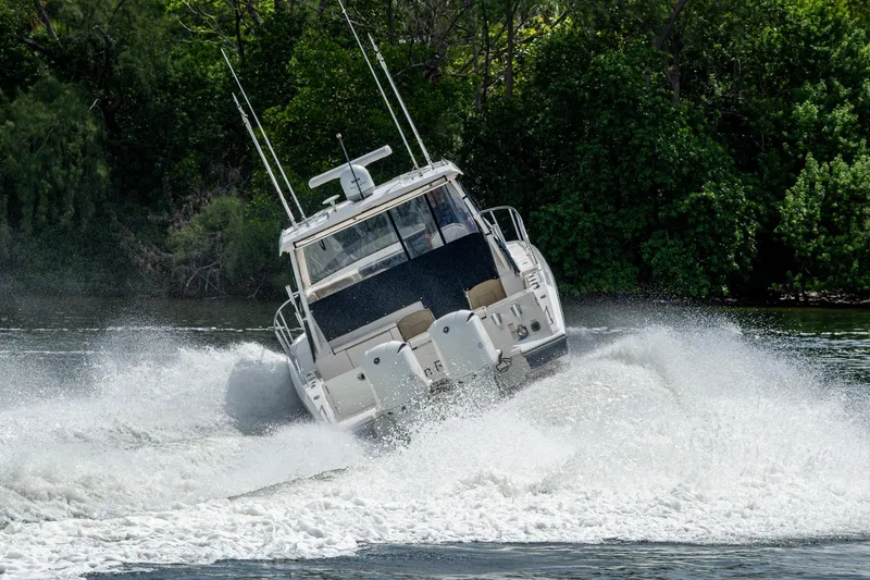 Slide: The Image of Powerful Pursuit boat navigating through water with lush green forest backdrop. - 79