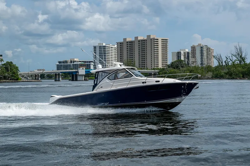 Slide: The Image of Pursuit boat cruising on water with city skyline in the background. - 8