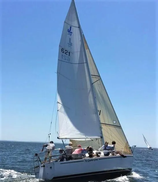 Slide: The Image of 1979 J Boats J 30 sailing on open water with crew, clear blue sky. - 4