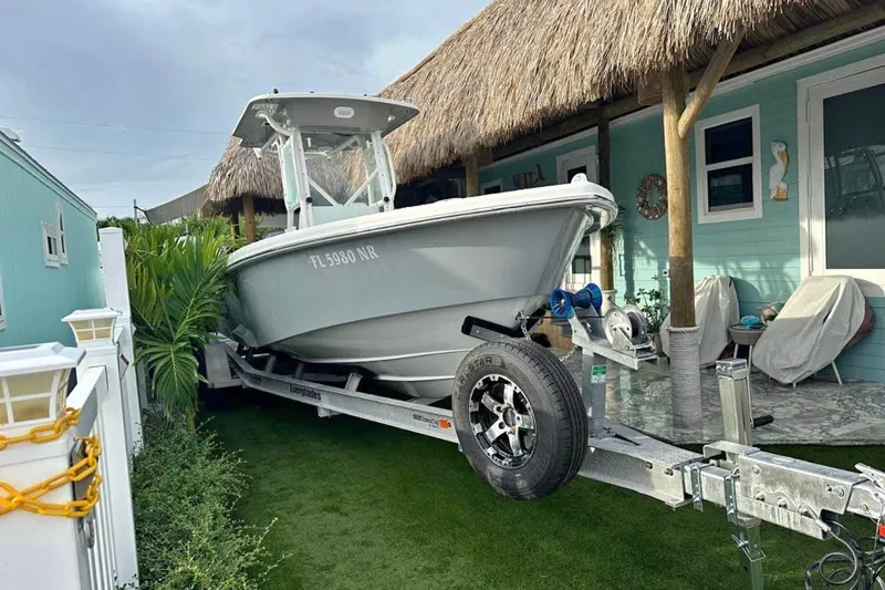 The Image of 2008 Everglades 243 Center Console boat on trailer beside a tropical-themed house. - 1