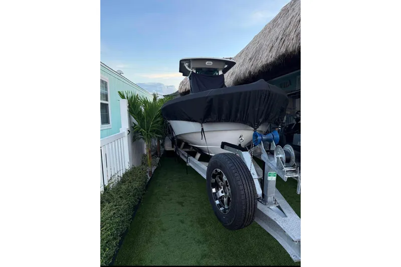 Slide: The Image of 2008 Everglades 243 Center Console boat on trailer, covered, beside a house with palm plants. - 9