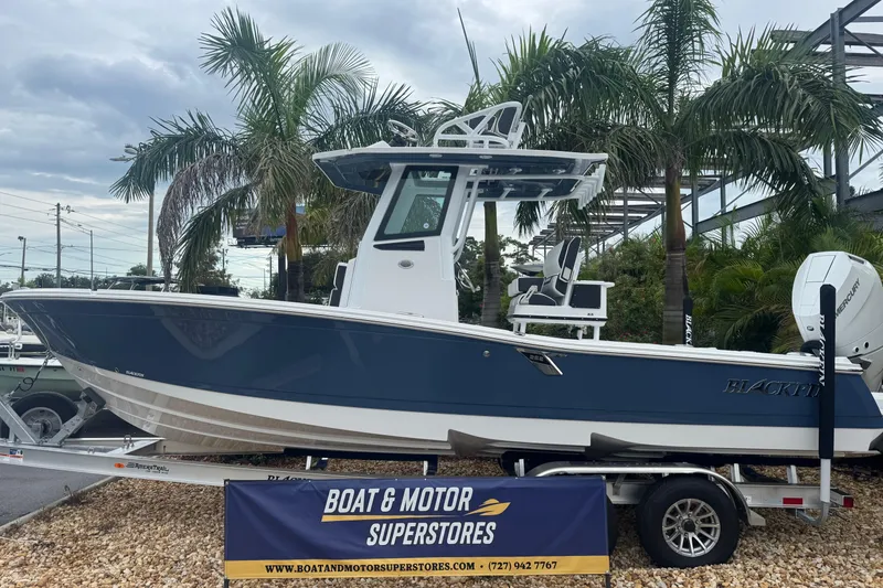 The Image of 2026 Blackfin 262 HB boat displayed at dealership with palm trees in background. - 1