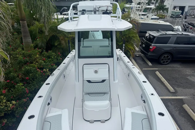 Slide: The Image of 2026 Blackfin 262 HB boat, sleek design, parked near lush greenery and vehicles. - 25