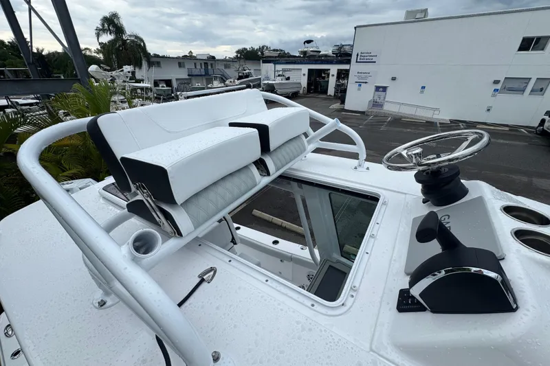 Slide: The Image of 2026 Blackfin 262 HB boat helm with steering wheel and seating, in a marina setting. - 28