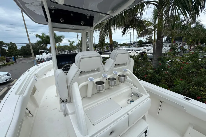 Slide: The Image of 2026 Key West 239 FS boat interior with seating and cup holders, surrounded by palm trees. - 10