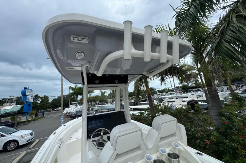 Slide: The Image of 2026 Key West 239 FS boat with T-top and rod holders, parked near palm trees. - 11