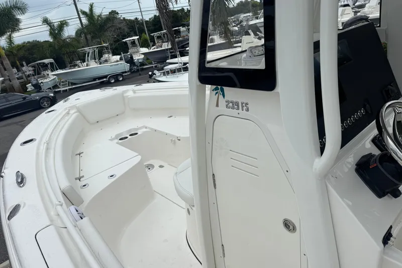 Slide: The Image of 2026 Key West 239 FS boat interior with seating and console, displayed outdoors. - 18