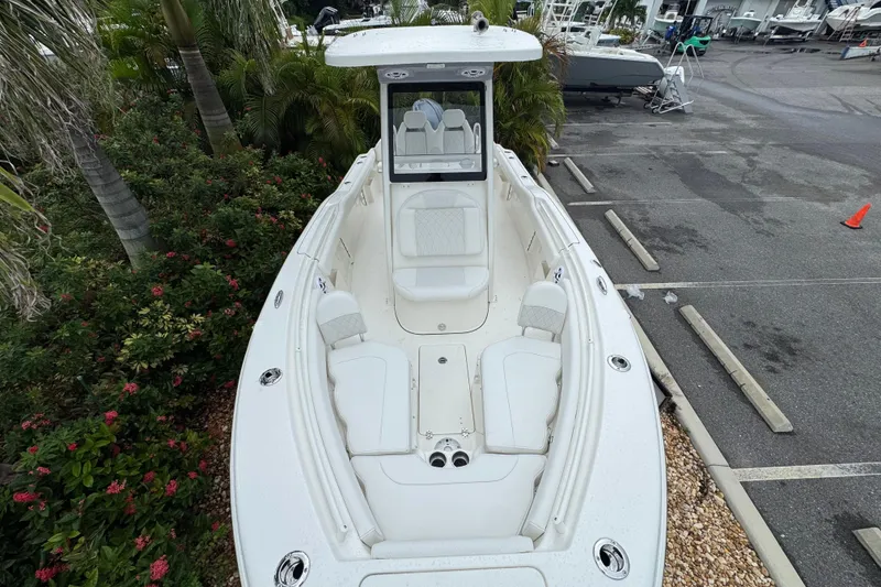 Slide: The Image of 2026 Key West 239 FS boat with spacious seating, parked near lush greenery. - 23