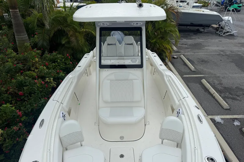 Slide: The Image of 2026 Key West 239 FS boat with white seating, parked near lush greenery. - 24