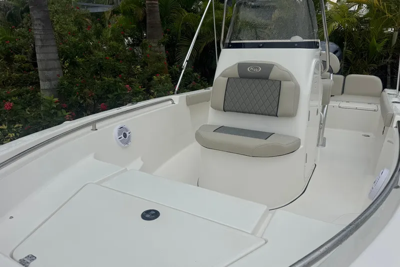 Slide: The Image of 2026 Key West 189 FS boat interior with seating and console, surrounded by lush greenery. - 17