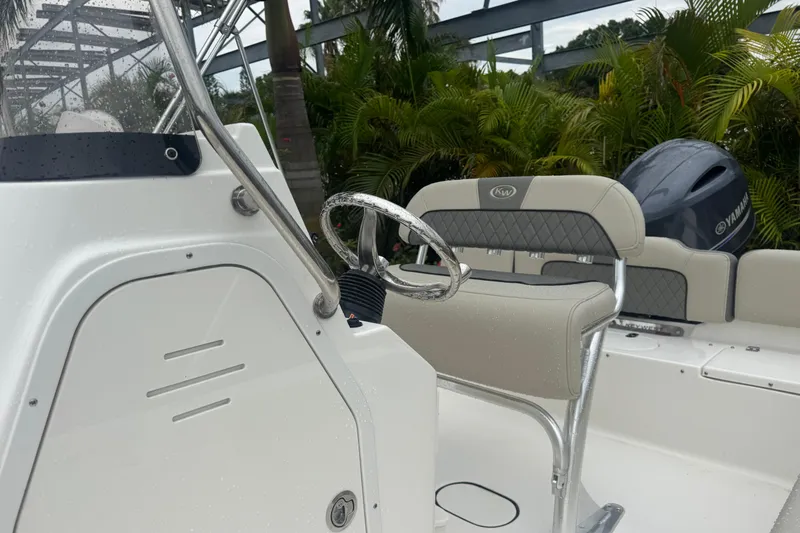 Slide: The Image of 2026 Key West 189 FS boat interior with steering wheel and seating, surrounded by lush greenery. - 18