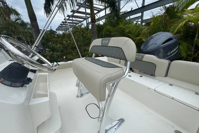 Slide: The Image of 2026 Key West 189 FS boat interior with steering wheel and seating, surrounded by lush greenery. - 19