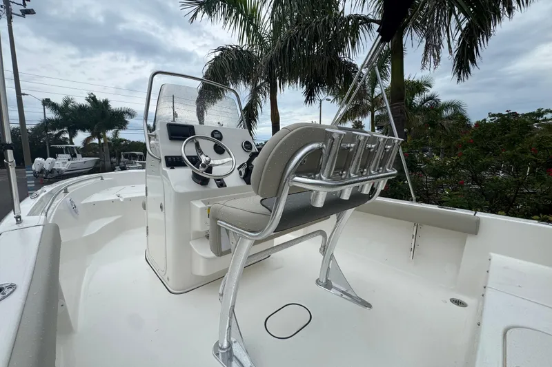 Slide: The Image of 2026 Key West 189 FS boat interior with steering console and seating, surrounded by palm trees. - 20