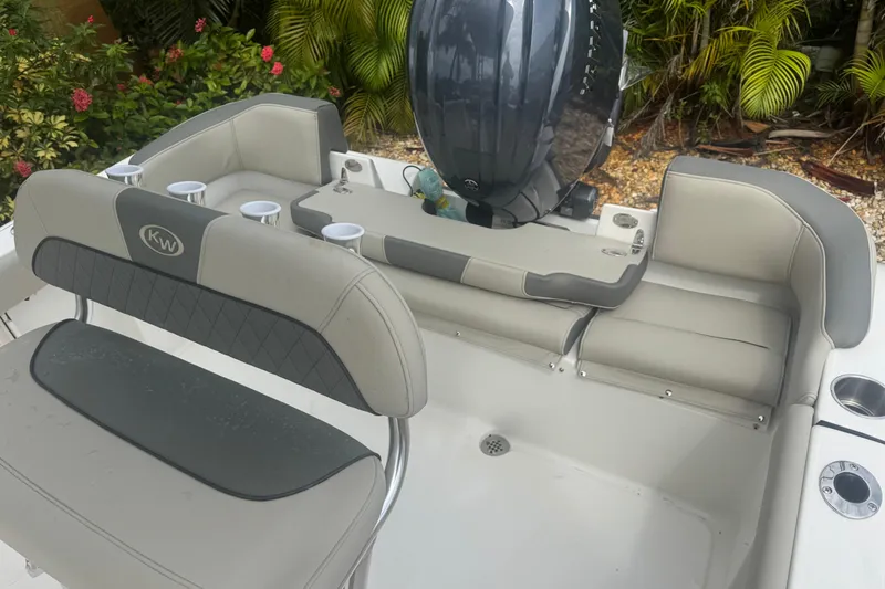 Slide: The Image of 2026 Key West 203 FS boat interior with seating and engine, surrounded by lush greenery. - 12