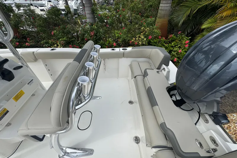 Slide: The Image of 2026 Key West 203 FS boat interior with seating and rod holders, surrounded by lush greenery. - 18