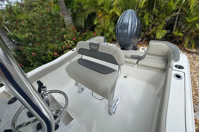 Slide: The Image of 2026 Key West 203 FS boat interior with seating and steering wheel, surrounded by lush greenery. - 9