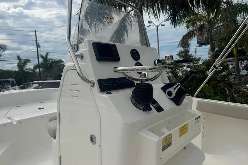 Slide: The Image of 2026 Key West 189 FS boat console with steering wheel and controls, surrounded by palm trees. - 15