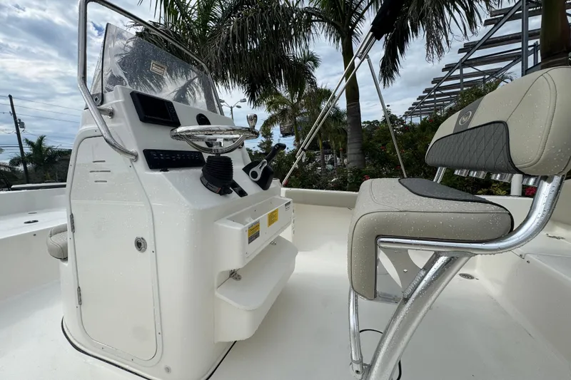 Slide: The Image of 2026 Key West 189 FS boat interior with steering console and seating, surrounded by palm trees. - 16