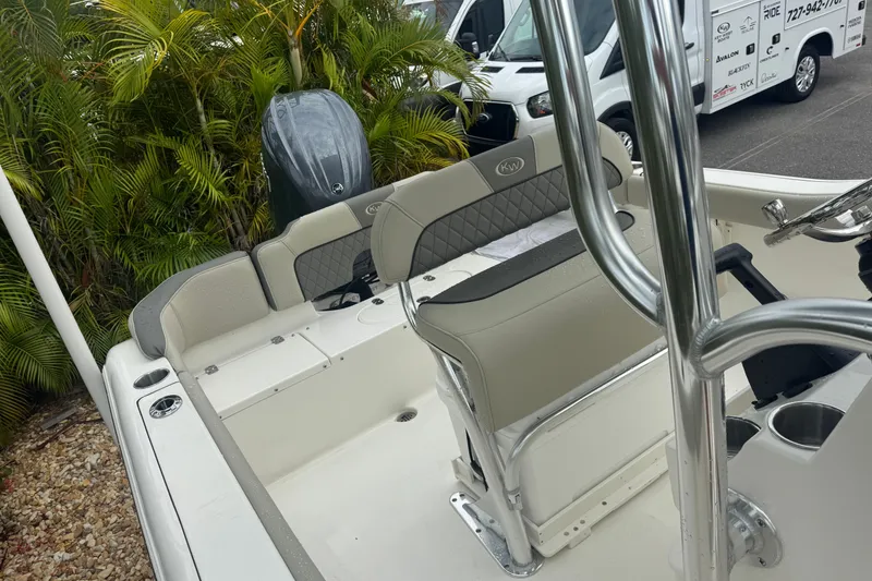 Slide: The Image of 2026 Key West 203 FS boat interior with seating and steering, parked near tropical plants. - 25
