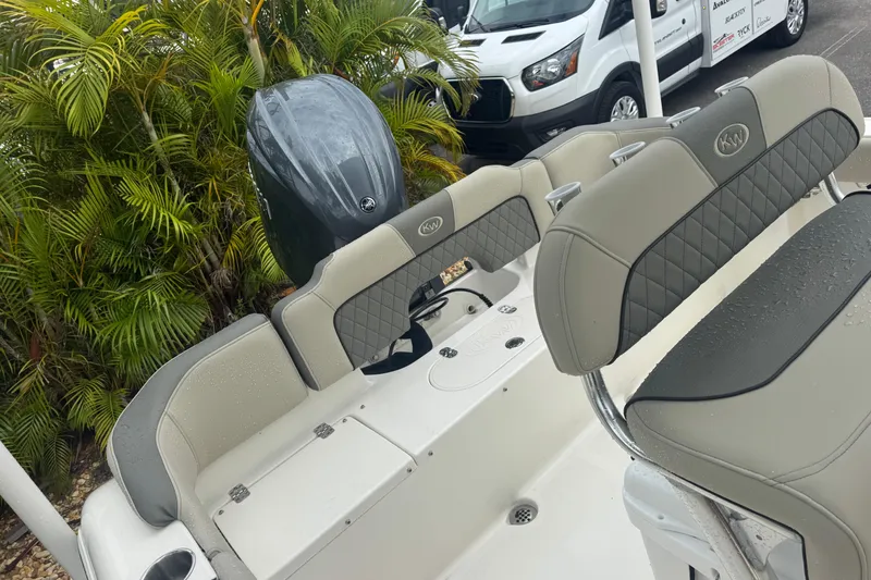 Slide: The Image of 2026 Key West 203 FS boat interior with seating and motor, parked near tropical plants. - 26