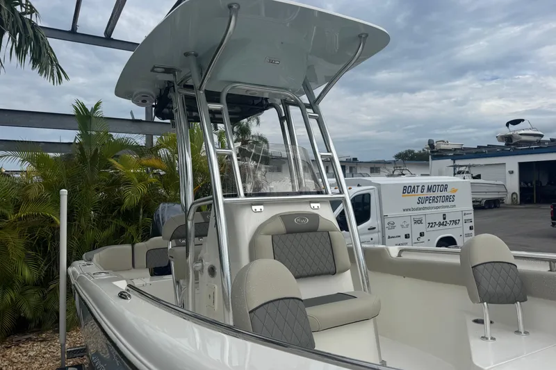 Slide: The Image of 2026 Key West 203 FS boat with T-top, parked near palm trees and a dealership. - 5