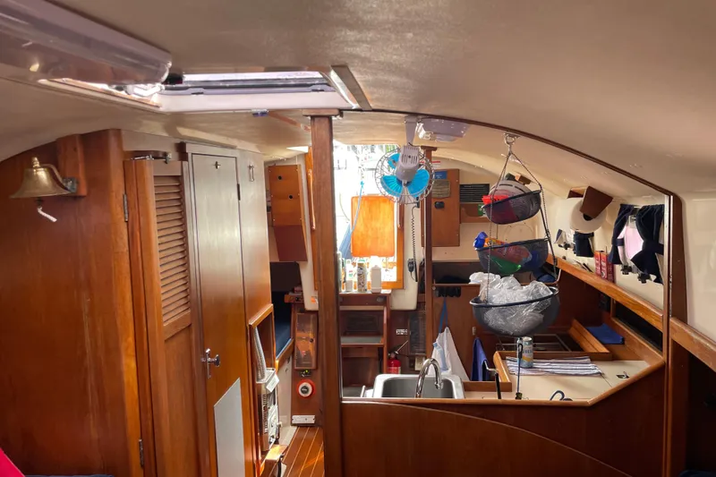 Slide: The Image of Interior of 1983 Nonsuch 30 Classic sailboat, featuring wooden cabinetry and compact kitchen area. - 13
