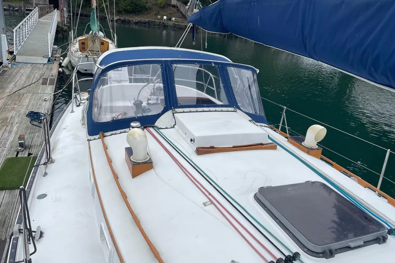 Slide: The Image of 1983 Nonsuch 30 Classic sailboat docked, featuring a spacious deck and blue canopy. - 3