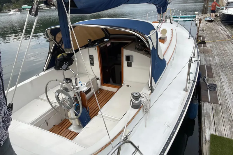 Slide: The Image of 1983 Nonsuch 30 Classic sailboat docked, featuring a spacious cockpit and blue canopy. - 5